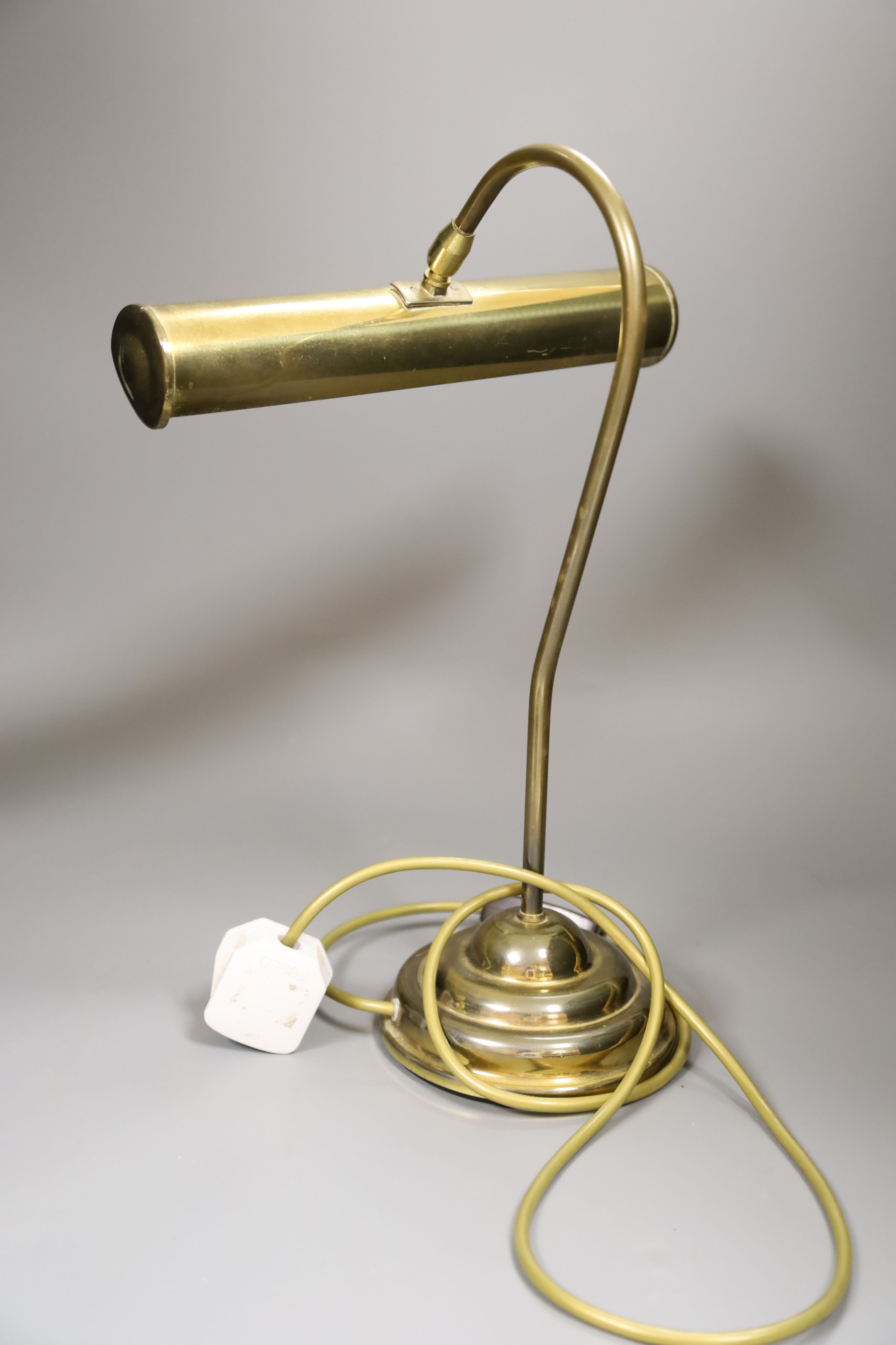 A copper overlaid fender, length 69cm, and a brass desk lamp